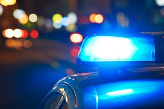 Close-up of a police car's blue light, with blurred lights in the background.