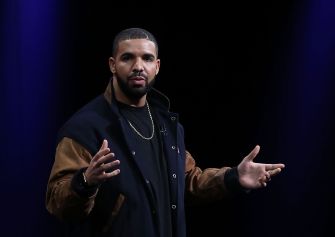 A person speaking on stage, gesturing with their hands.