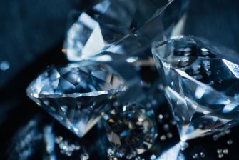Close-up image of sparkling diamonds on a dark surface.