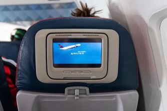 Delta in-flight entertainment screen built into a blue seat back displaying the Delta logo and “Keep Climbing.”