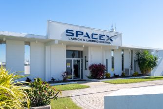 Exterior view of SpaceX Launch and Landing Control building with landscaping under a clear blue sky.