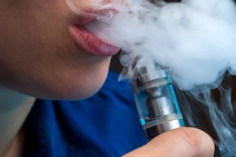 Close-up of a person exhaling vapor from an e-cigarette or vaping device.