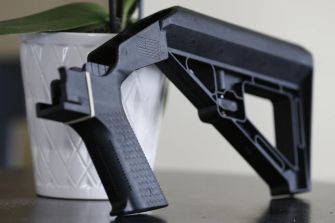 Image of a bump stock firearm accessory placed next to a plant.