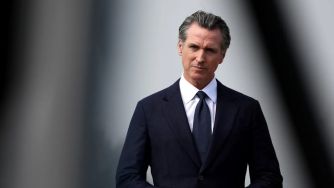 Governor Gavin Newsom speaking on a political issue, with a serious expression.