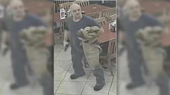 Surveillance image of a diner holding a gun inside a restaurant during a robbery.