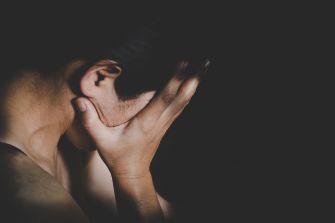 A person with their head down, covering their face with their hand, expressing distress or sorrow.