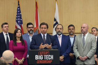 Governor DeSantis speaks at a press conference about the Stop Social Media Censorship Act, flanked by supporters in front of a sign that reads "STOP BIG TECH CENSORSHIP."