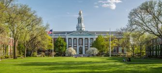 A view of the Harvard University campus featuring the iconic building with a flag and surrounding greenery.