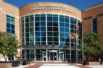 Baltimore City Juvenile Justice Center exterior with large glass windows and a banner overhead.