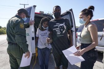 A border patrol agent interacts with a Haitian family recently detained, as they navigate the complexities of migration and border policies in the United States.