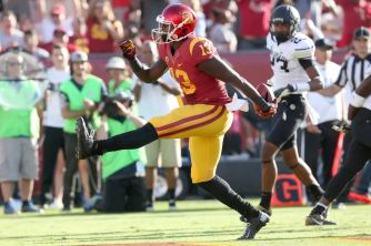 A football player in a USC uniform running on the field during a game.