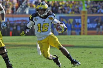 Denard Robinson running with the football during a game as a University of Michigan player.