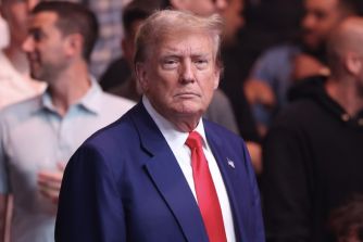 Former President Donald Trump at a public event, amidst a crowded background.