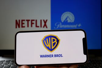 Close-up of a display with the Netflix logo on the left, a Paramount+ emblem in blue in the background, and a Warner Bros. shield logo on a foreground card.
