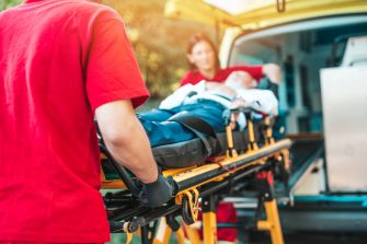 An emergency medical team transporting a patient on a stretcher into an ambulance.