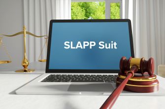 A gavel and laptop featuring the text "SLAPP Suit" on the screen, symbolizing legal discussions on anti-SLAPP laws.