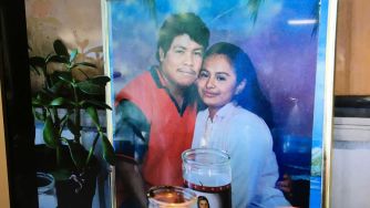 A framed photo of a man and woman together, with candles placed in front of it.