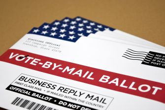 A stack of vote-by-mail ballots featuring a U.S. flag design.