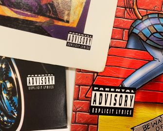Close-up of colorful album covers with large "Parental Advisory Explicit Lyrics" labels.