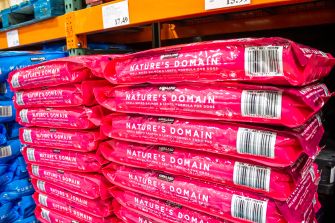 Stacks of pink Nature's Domain dog food bags on a store shelf.