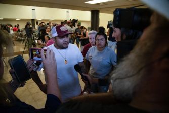 A man speaking to the media surrounded by several individuals after the release of the Uvalde school shooting investigation report.