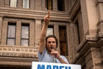 Matthew McConaughey gestures while speaking at a rally, advocating for community engagement in Texas.