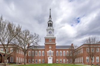 The iconic Dartmouth College campus with its distinctive clock tower and historic brick buildings under a cloudy sky.