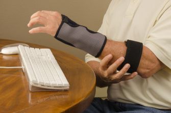 A man wearing an arm brace while typing on a keyboard.
