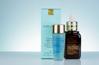 Estée Lauder skincare and fragrance products, including a blue box and glass bottles, on a light blue background.