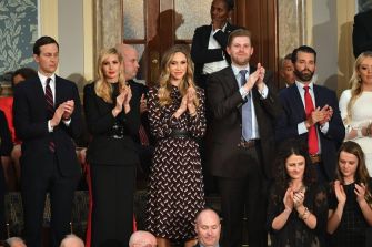 A group of individuals, including family members and advisors, clapping and attending an event in a formal setting.