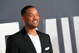 Smiling man in a black suit and white shirt at a formal event.