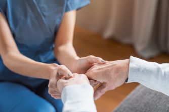 A caregiver holding hands with an elderly person, symbolizing support and care.