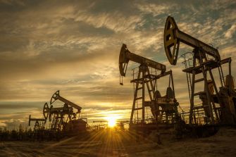 Oil drilling rigs at sunset with a dramatic sky.