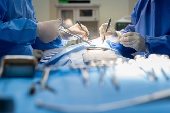 Surgical team performing an operation with medical instruments arranged on a tray.