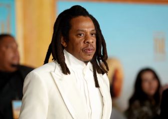 Jay-Z at a public event, wearing a white suit.
