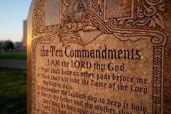 Close-up of a granite monument engraved with the Ten Commandments and a decorative border, featuring the Eye of Providence emblem at the top.