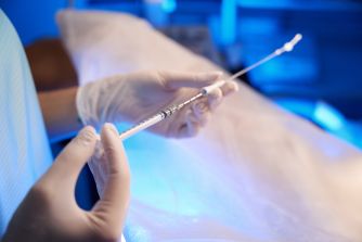 A healthcare professional holding a medical syringe in a clinical setting, related to fertility treatments.