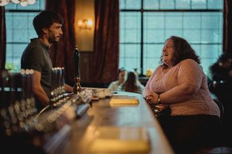 A scene from the Netflix series "Baby Reindeer" featuring two characters interacting at a bar.