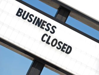 A sign that reads "BUSINESS CLOSED" against a blue sky background.