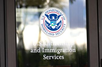Glass door displaying the U.S. Department of Homeland Security seal and the words U.S. Citizenship and Immigration Services.