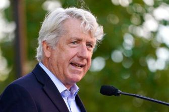 A man with gray hair speaking into a microphone at an outdoor event.