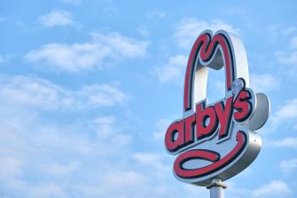 Arby’s restaurant sign against a blue sky with clouds.