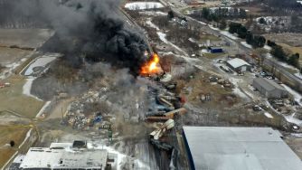 Aerial view of the train derailment site in East Palestine, Ohio, showing dark smoke and fire from the incident.