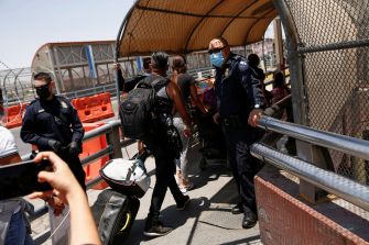 A group of individuals, including police officers, at a border crossing, as migrants prepare to cross into the United States.