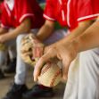 A baseball player holding a ball while seated on a bench during a game.