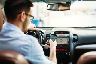 A person texting on a smartphone while driving a car.